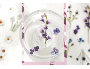 Close-up detail of purple floral PET stickers, transparent glass dish display, journaling DIY.