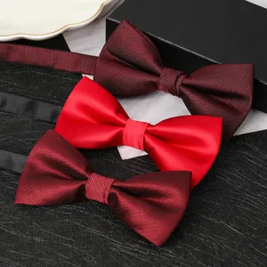 Close-up detail of burgundy and red formal bowties on textured background for wedding suit.