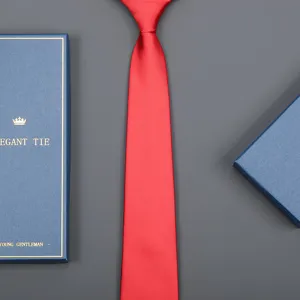Close-up detail of a vibrant red business tie displayed neatly beside an elegant blue gift box.