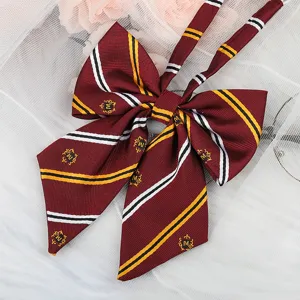 Dark red JK school style bow tie with diagonal stripes and embroidered M crest badge detail.