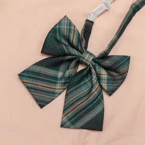 Close-up detail of a dark green plaid JK uniform bow tie with adjustable white strap.