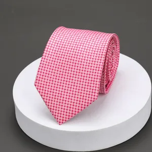 Detail view of a stylish pink patterned necktie neatly rolled on a white display podium.