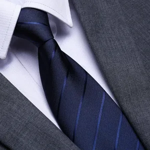 Close-up of mens classic navy blue striped tie with white dress shirt and grey suit jacket.