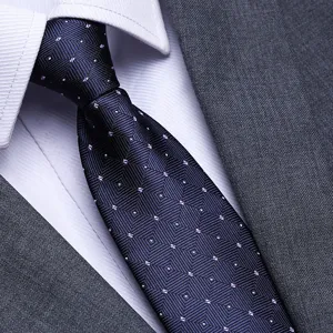 Close-up of a men's navy blue patterned business tie with white shirt and grey suit.