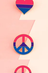 Enamel pin detail showing vibrant pink purple and blue heart and peace sign brooch.