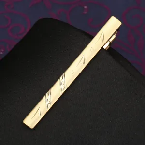 Golden men's tie clip with elegant engraved pattern, classic business formal metal pin.