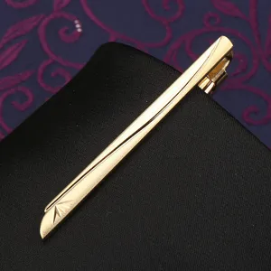 Golden metal tie clip detail, sleek streamlined design with delicate engraving for formal suit.