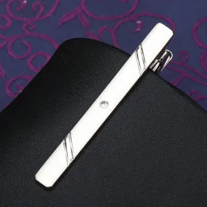 Close up of a sleek silver tie clip featuring elegant striped engravings and a sparkling crystal.