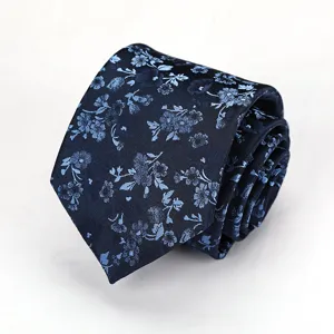 Close-up detail of dark blue necktie featuring delicate light blue floral pattern texture.