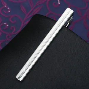 Silver metal tie clip detail close up showcasing polished surface and modern striped design texture.