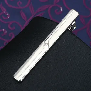Close-up of a sleek silver metal tie clip featuring a sparkling crystal rhinestone detail.