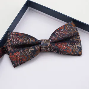 Dettaglio papillon con classico motivo cachemire, che mostra elegante tessuto blu scuro.