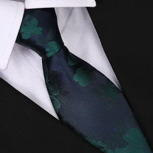 Close-up detail shot of the dark blue necktie featuring retro green floral patterns.