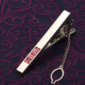 Vue détaillée d'un pince-cravate argenté pour homme avec trois pierres roses et une fine chaînette.