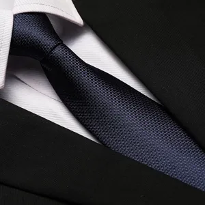 Detail view of a classic navy blue textured business necktie paired with white shirt and black suit.