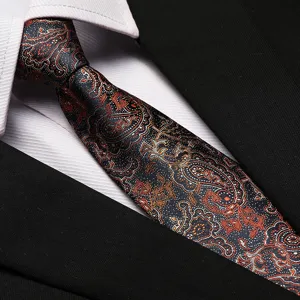 Detailed view of luxury paisley silk necktie with intricate orange and black floral patterns.