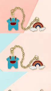Detailed view of creative rainbow cloud and overalls brooch pin connected by gold chain.