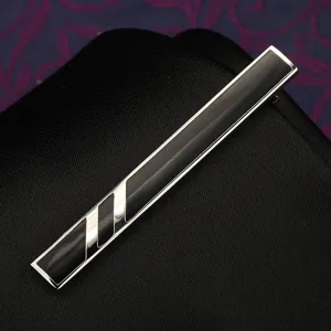 Primo piano dettagliato di un fermacravatta in metallo argentato con inserti geometrici neri.