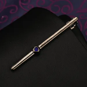 Primo piano di un'elegante fermacravatta argento con brillante pietra di cristallo blu.