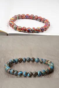 Gros plan détaillé de bracelets élastiques en perles rondes aux rayures colorées et uniques.