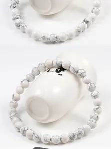 Gros plan sur le bracelet de perles élastiques en howlite blanche avec texture marbrée naturelle.