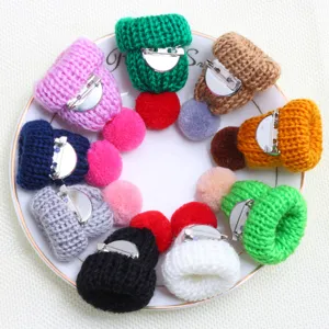 Close-up of colorful knitted mini hat brooches featuring fluffy pom-poms and pin backs.