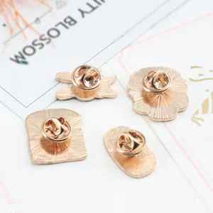 Close-up back view of golden alloy enamel food pins showcasing secure metal clutch fasteners.