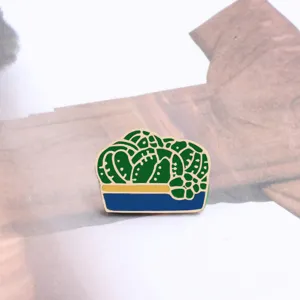 Primo piano dettagliato di una simpatica spilla smaltata con pianta verde e vaso blu.