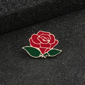 Primo piano dettagliato di una deliziosa spilla in metallo smaltato a forma di rosa rossa con foglie.