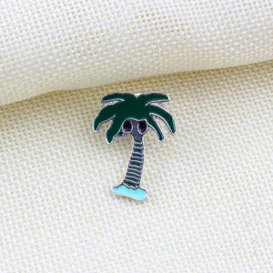 Close-up detail view of a green palm tree enamel lapel pin brooch on woven fabric.