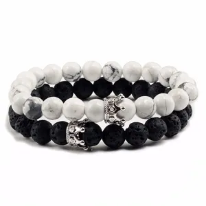 Primo piano di bracciali di coppia in turchese bianco e lava nera con ciondoli a corona d'argento.