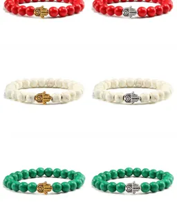 Détail de bracelet yoga en perles de turquoise avec breloque main de hamsa dorée.