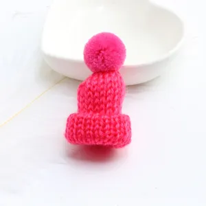 Close-up detail of the mini pink knitted wool hat pendant, showing fine yarn texture and cute pom-pom.