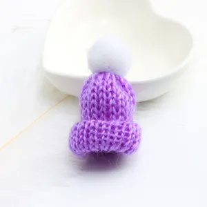 Close-up detail of a cute purple knitted mini beanie hat with a fluffy white pom-pom charm.