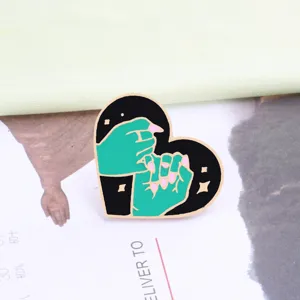 Detail shot of cute heart enamel brooch pin featuring pinky promise design for bags.