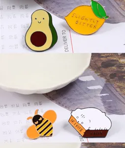 Enamel pin detail close-up showing cute cartoon avocado lemon bee and cat brooches.
