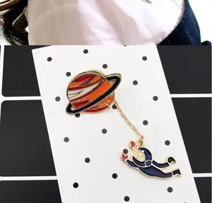 Detail shot of the creative planet and astronaut alloy brooch with dangling chain design.
