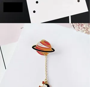 Detailed shot of creative planet and astronaut alloy brooch with chain, enamel pin.