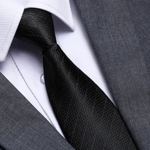 Primo piano dettagliato di una cravatta nera testurizzata da uomo con camicia e abito.