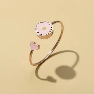 Roségouden open armband met een schattig roze madeliefje en een mooie hartvormige bedel.