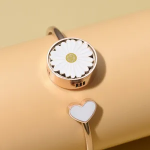 Detailopname van een roségouden madeliefje armband met wit hartje en ventilatieopeningen.