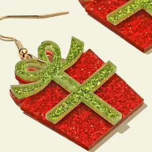 Close-up detail of Christmas gift box acrylic earrings with sparkly red and green glitter finish.
