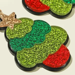 Close-up detail of glitter Christmas tree acrylic earrings with star and metal ring.