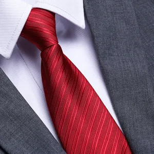 Close-up detail of a classic red textured necktie paired with white shirt and grey suit.