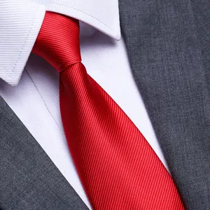 Close-up of a classic red business necktie paired with a crisp white shirt and a sleek gray suit.