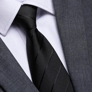 Primo piano di una cravatta formale nera classica testurizzata con camicia e abito.