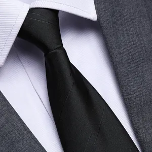 Dettaglio in primo piano di cravatta nera formale abbinata a camicia bianca e abito.