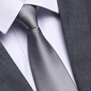 Cravatta in seta grigia classica abbinata a camicia bianca e giacca elegante per affari.