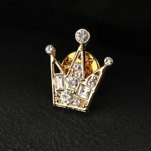 Spilla corona oro con strass trasparenti, primo piano dettaglio accessorio moda uomo.
