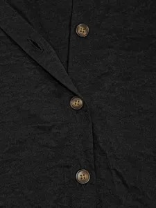 Gros plan détaillé d'un vêtement en tissu texturé foncé avec des boutons et des coutures.